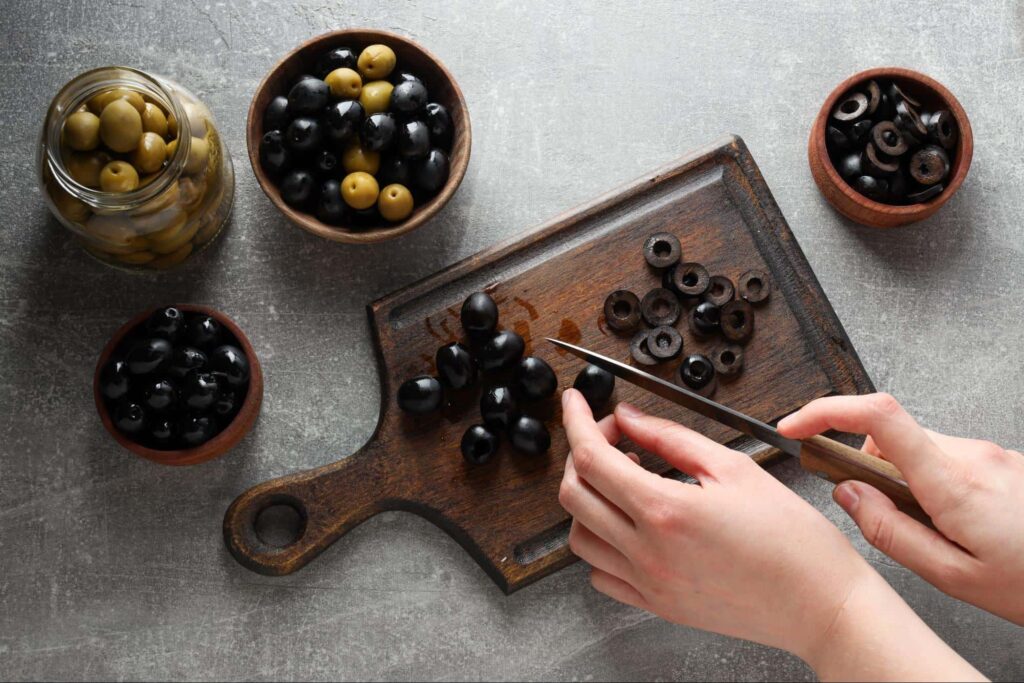 kobieta krojąca oliwki na plasterki